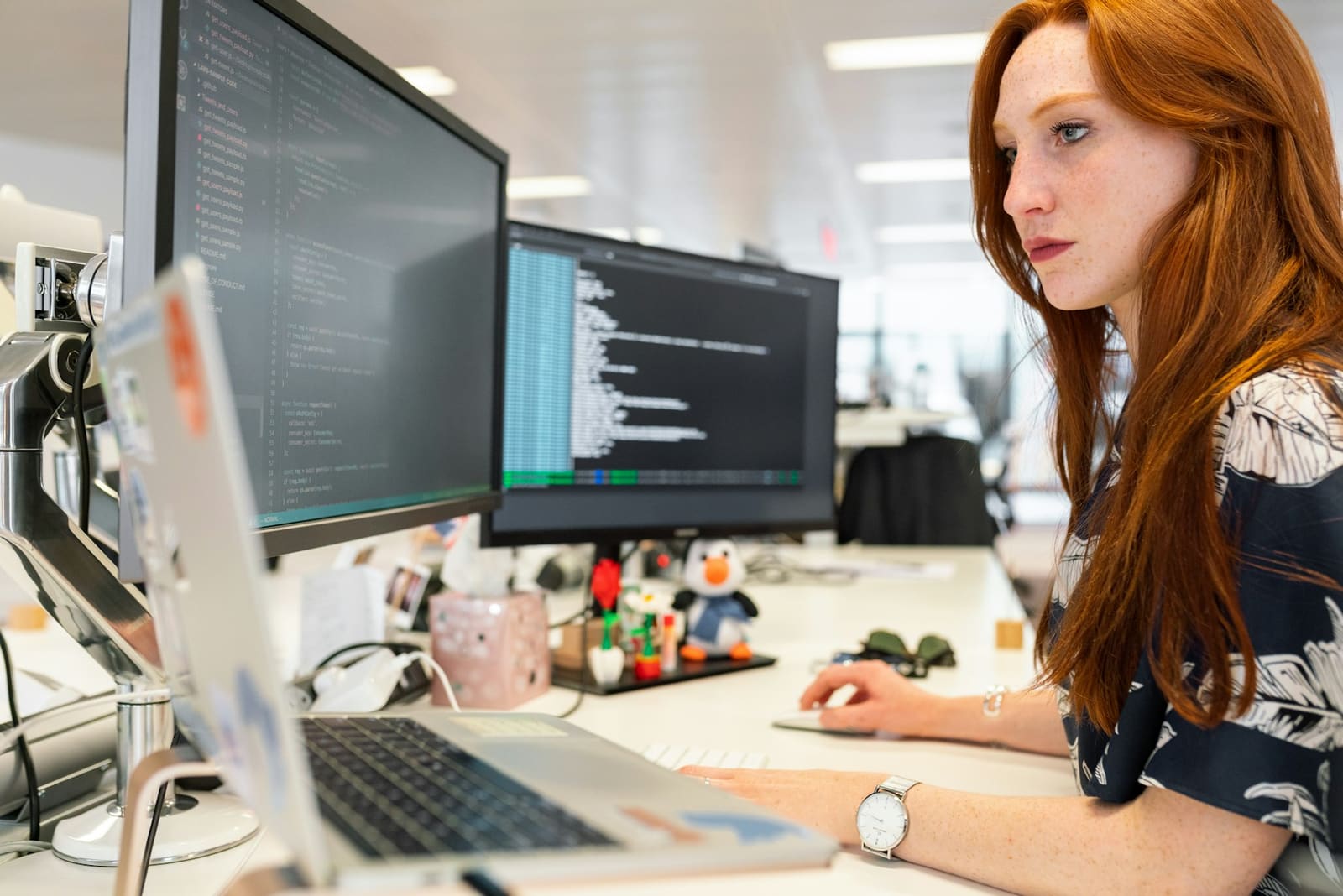 An engineer reviewing code on two monitors